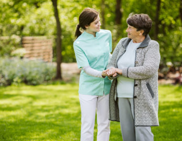 Nurse and patient in the garden of modern senior home with daily care